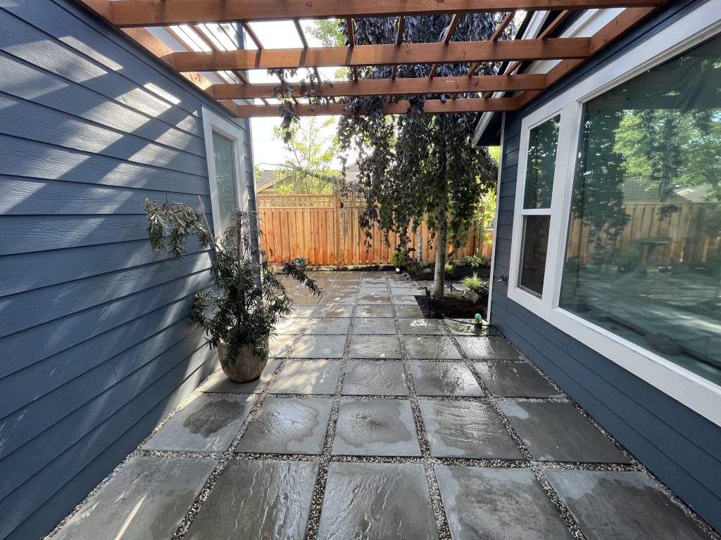 A stone walkway beneath a timber pergola.